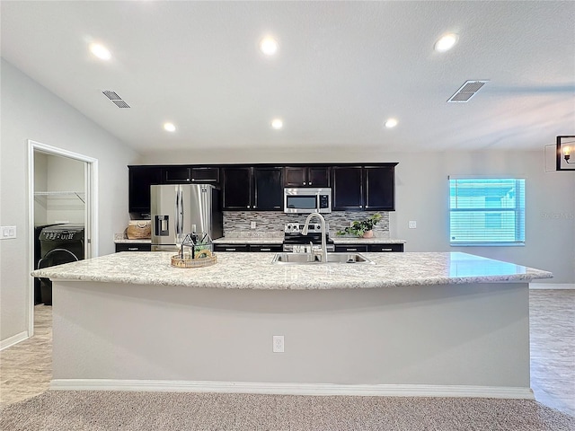 kitchen with visible vents, a large island with sink, a sink, stainless steel appliances, and dark cabinets