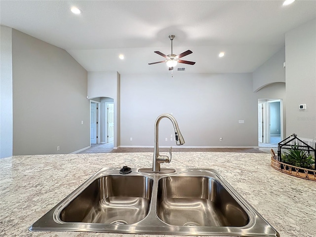 kitchen featuring arched walkways, vaulted ceiling, open floor plan, and a sink