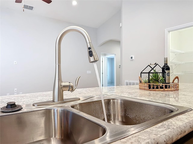 interior details with light countertops, a ceiling fan, visible vents, and arched walkways