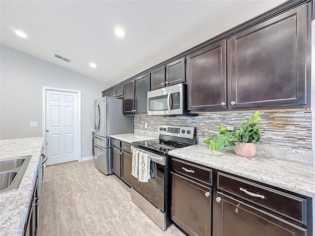 kitchen featuring visible vents, backsplash, dark brown cabinetry, lofted ceiling, and appliances with stainless steel finishes