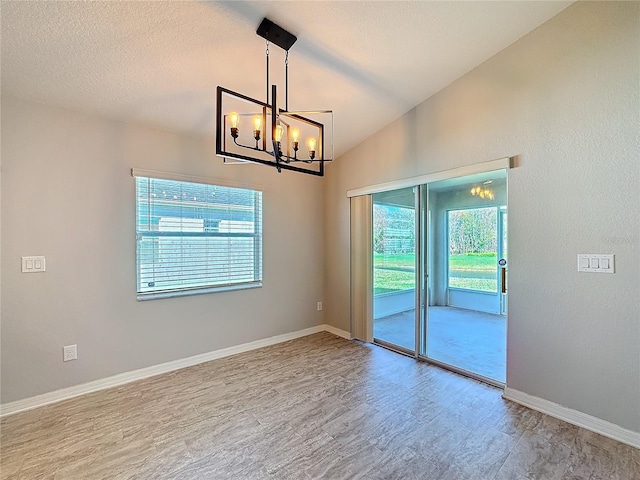 unfurnished room with baseboards, lofted ceiling, an inviting chandelier, wood finished floors, and a textured ceiling