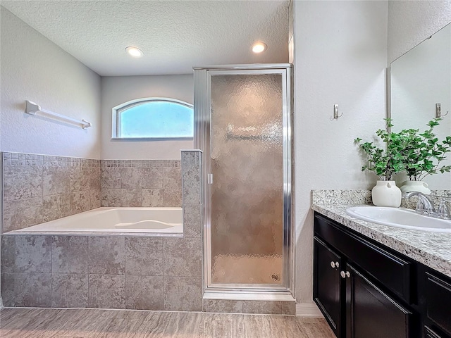 bathroom featuring vanity, a textured ceiling, a bath, and a shower stall