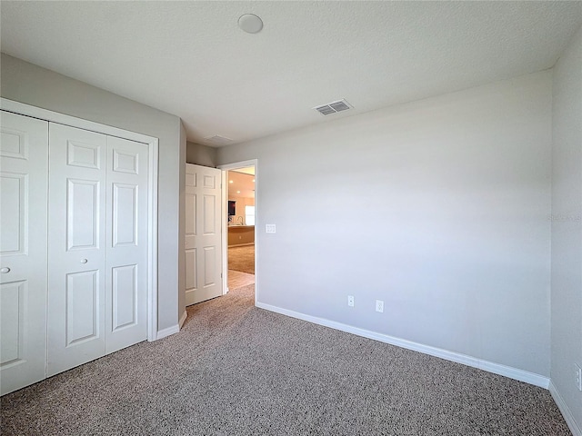 unfurnished bedroom featuring visible vents, baseboards, carpet, and a closet