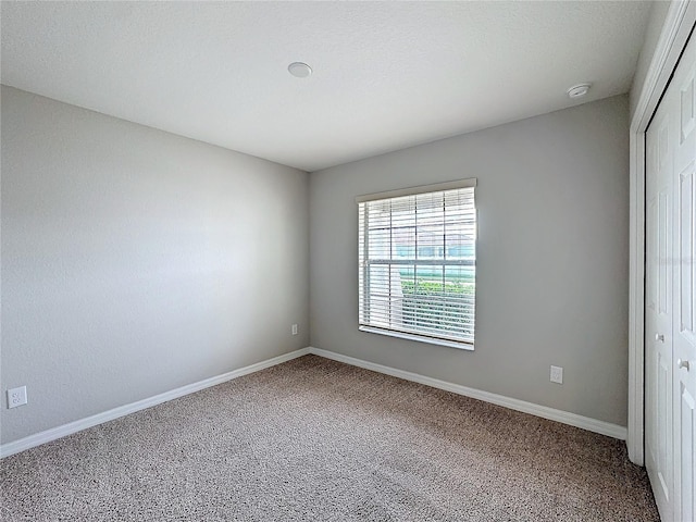 interior space featuring carpet, baseboards, a closet, and a textured ceiling