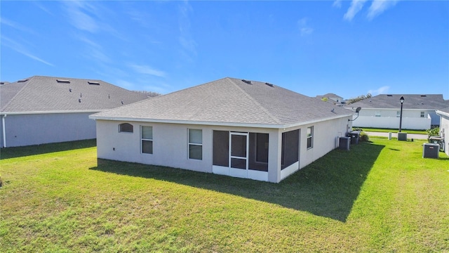 back of house with stucco siding, a yard, cooling unit, and a shingled roof