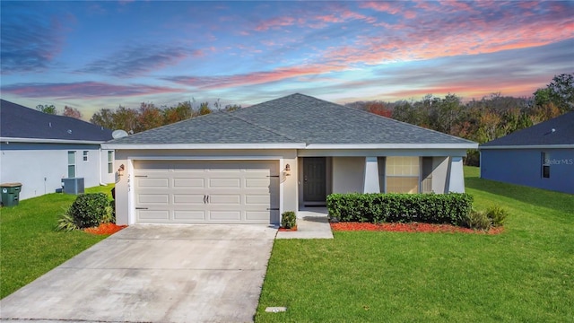 ranch-style house featuring a shingled roof, a front lawn, central AC unit, stucco siding, and a garage