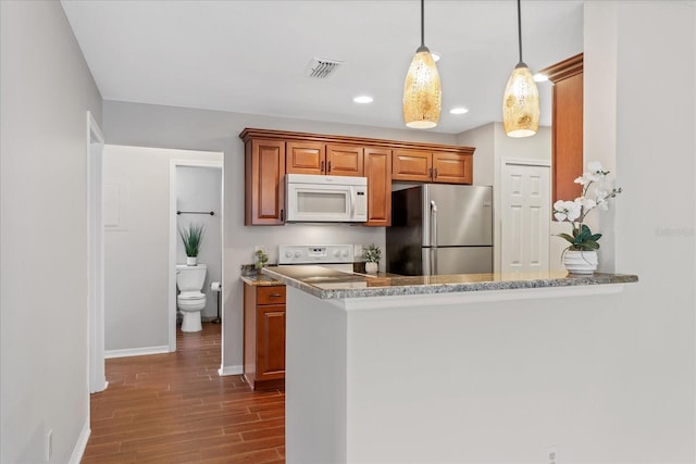 kitchen with white microwave, stove, visible vents, freestanding refrigerator, and decorative light fixtures