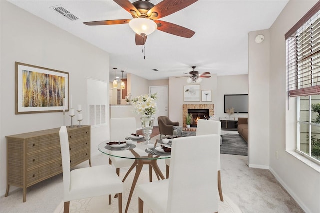 dining area with baseboards, a fireplace, visible vents, and light colored carpet