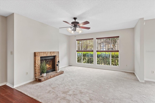 unfurnished living room featuring a ceiling fan, a brick fireplace, a textured ceiling, and baseboards