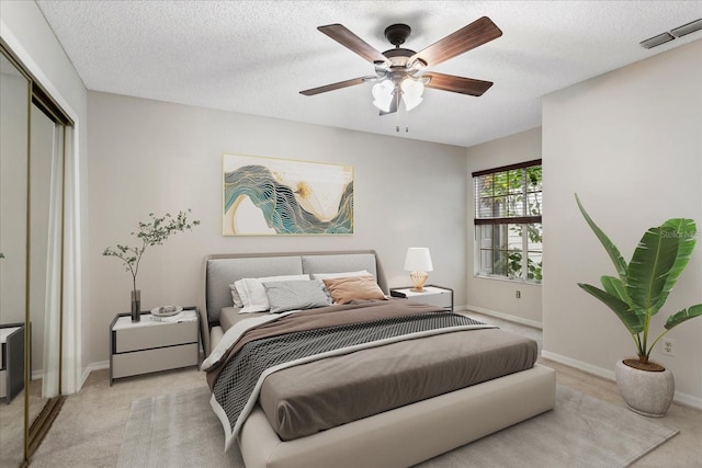 bedroom featuring light carpet, a textured ceiling, and visible vents