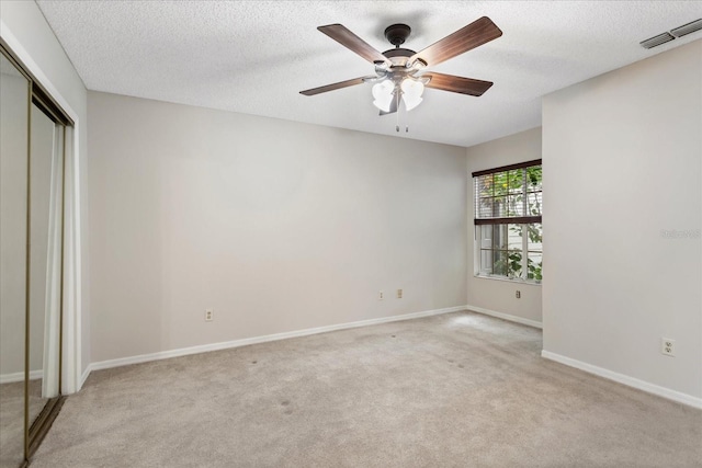 interior space featuring light carpet, baseboards, visible vents, a textured ceiling, and a closet