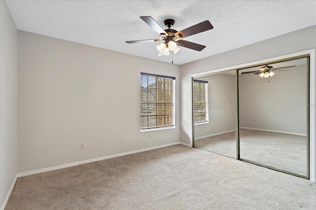 unfurnished bedroom with light carpet, a closet, a textured ceiling, and baseboards