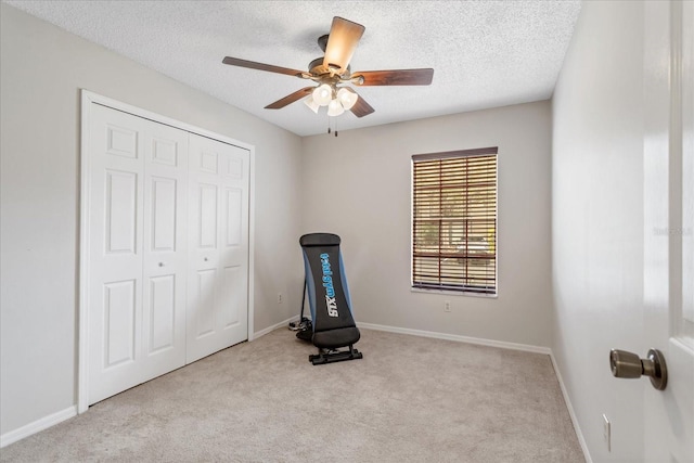 workout room with ceiling fan, baseboards, a textured ceiling, and light colored carpet