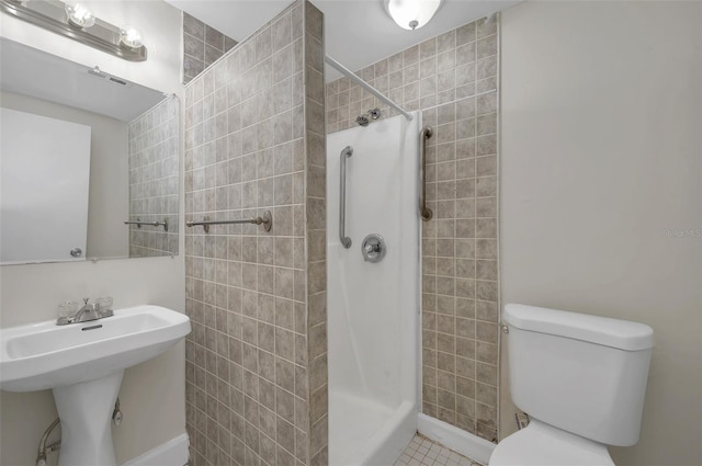 bathroom featuring sink, a tile shower, and toilet