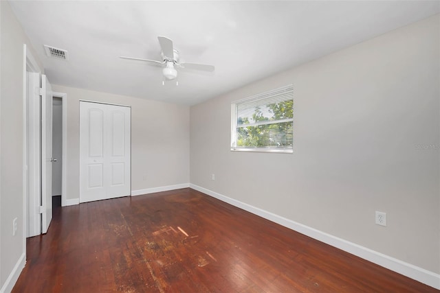 unfurnished bedroom featuring a closet, dark hardwood / wood-style floors, and ceiling fan