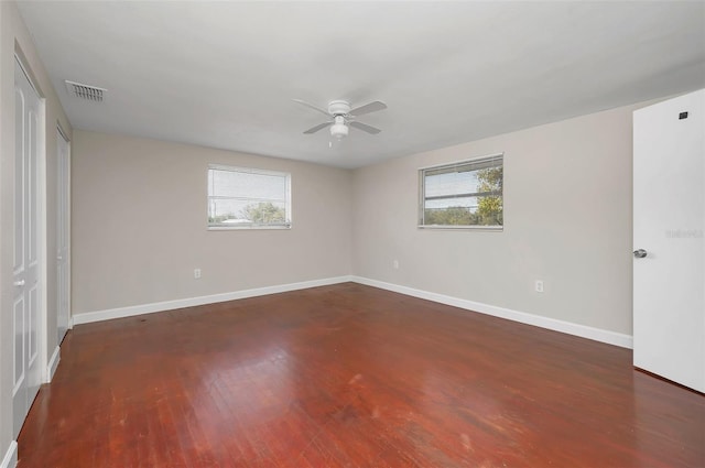 spare room featuring dark wood-type flooring, plenty of natural light, and ceiling fan