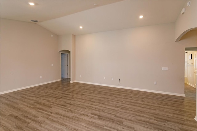 empty room with hardwood / wood-style flooring and vaulted ceiling