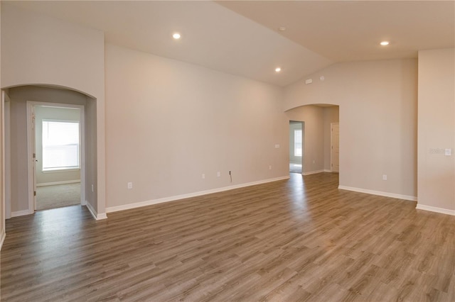 empty room featuring high vaulted ceiling and light hardwood / wood-style floors