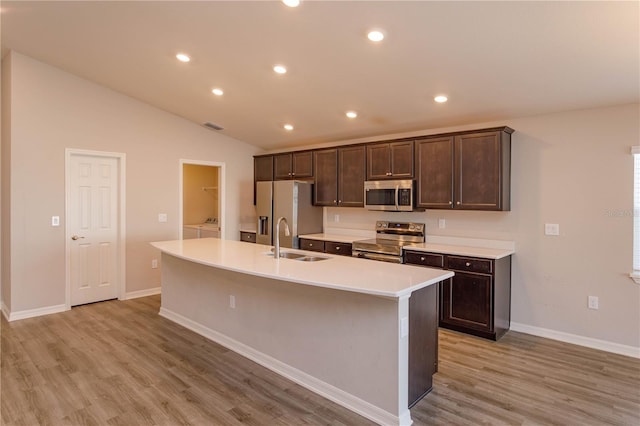 kitchen with stainless steel appliances, sink, separate washer and dryer, and an island with sink