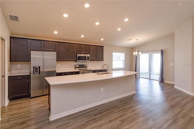 kitchen featuring sink, light hardwood / wood-style flooring, stainless steel appliances, a center island with sink, and decorative light fixtures