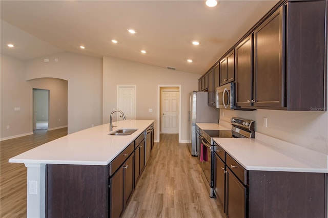 kitchen featuring lofted ceiling, stainless steel appliances, sink, and a center island with sink