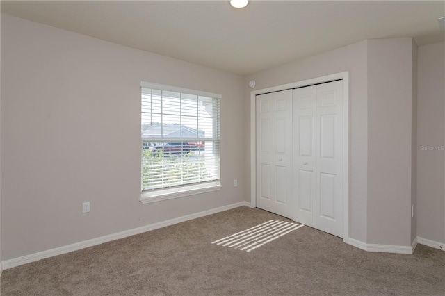 unfurnished bedroom with light colored carpet and a closet