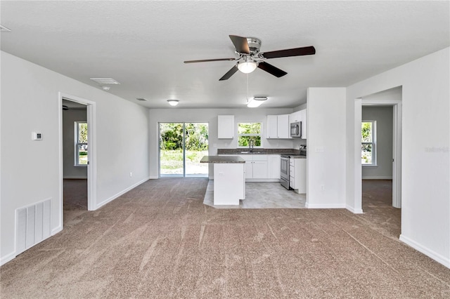 kitchen with appliances with stainless steel finishes, a center island, white cabinets, and plenty of natural light