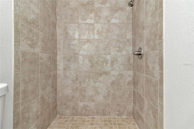 bathroom featuring a tile shower and toilet