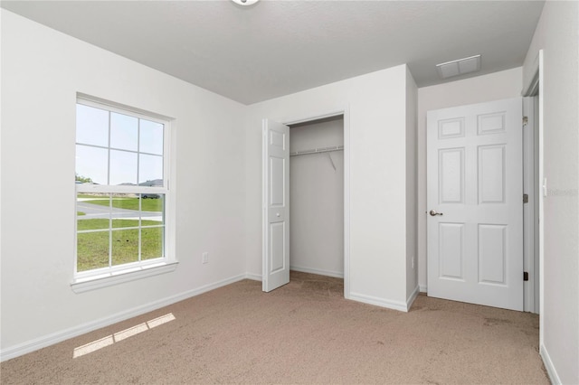 unfurnished bedroom featuring light colored carpet and a closet