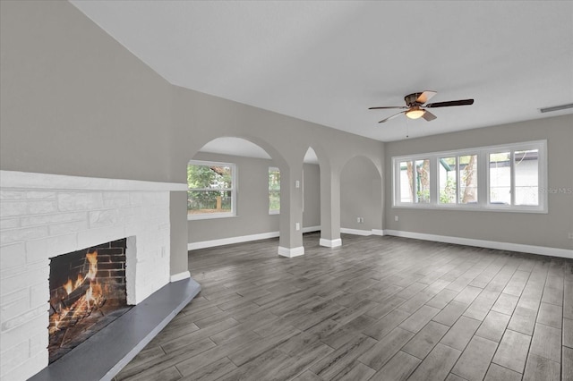 unfurnished living room with hardwood / wood-style flooring, ceiling fan, and a brick fireplace