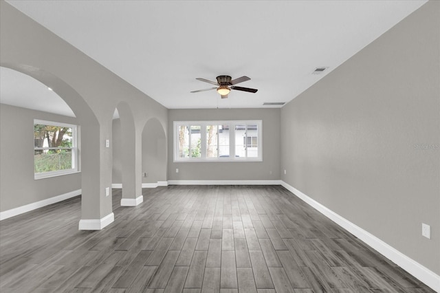 unfurnished living room featuring ceiling fan, plenty of natural light, and dark hardwood / wood-style flooring