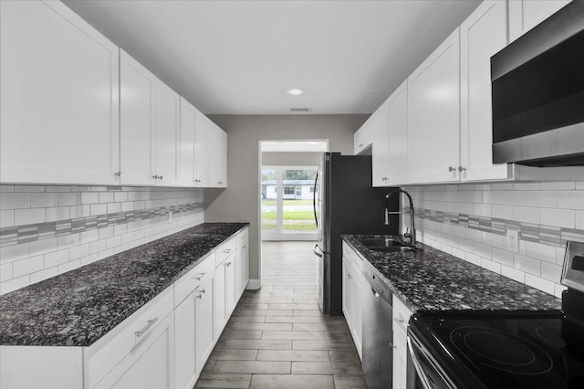 kitchen featuring sink, white cabinetry, tasteful backsplash, dark stone counters, and stainless steel appliances