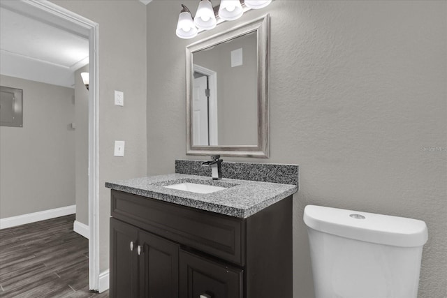 bathroom featuring hardwood / wood-style flooring, vanity, toilet, and electric panel