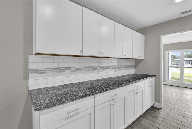 kitchen featuring white cabinetry, tasteful backsplash, and dark stone counters