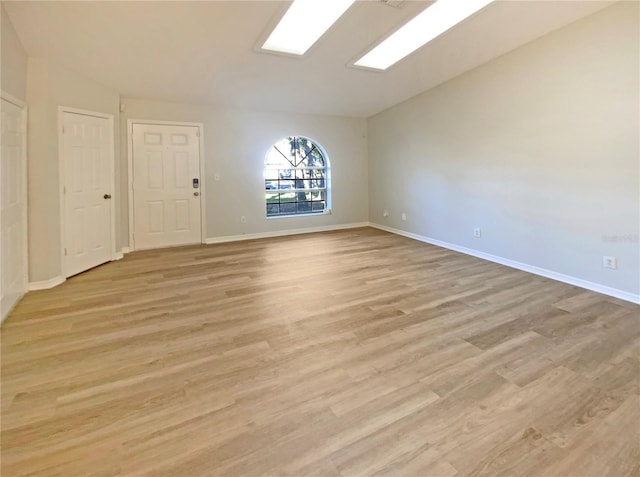 empty room with lofted ceiling and light hardwood / wood-style floors