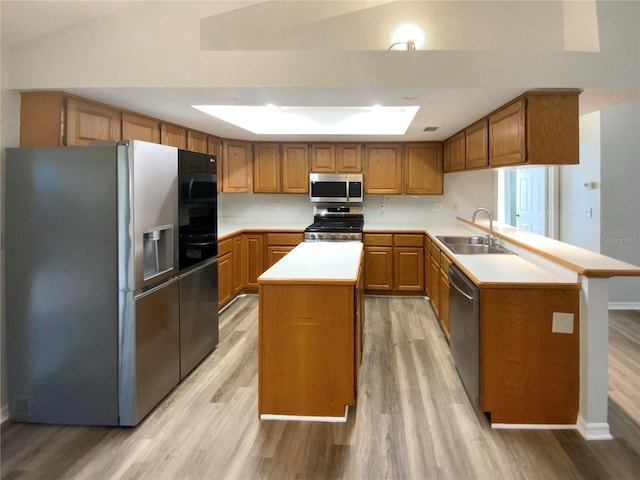 kitchen with appliances with stainless steel finishes, sink, a center island, and light wood-type flooring