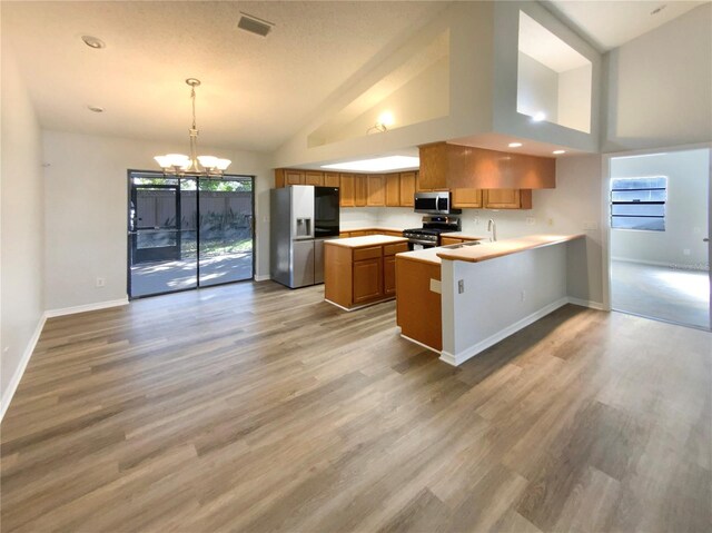 kitchen featuring a chandelier, pendant lighting, a kitchen island, stainless steel appliances, and kitchen peninsula