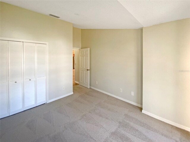 unfurnished bedroom with a closet, vaulted ceiling, and light colored carpet