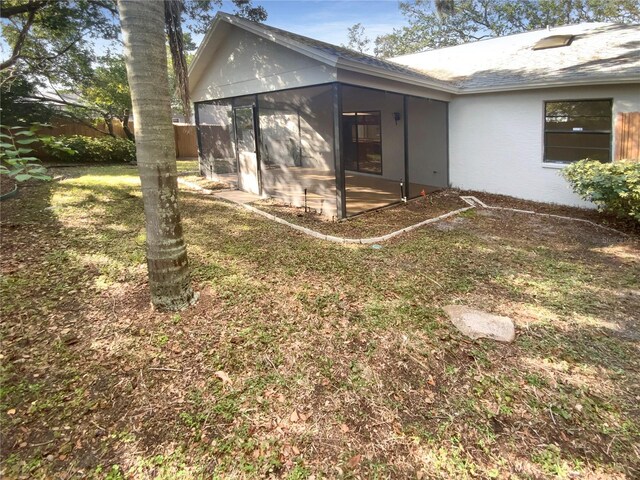 view of property exterior with a sunroom and a lawn