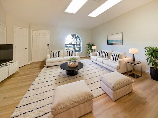 living room with vaulted ceiling with skylight and light hardwood / wood-style floors