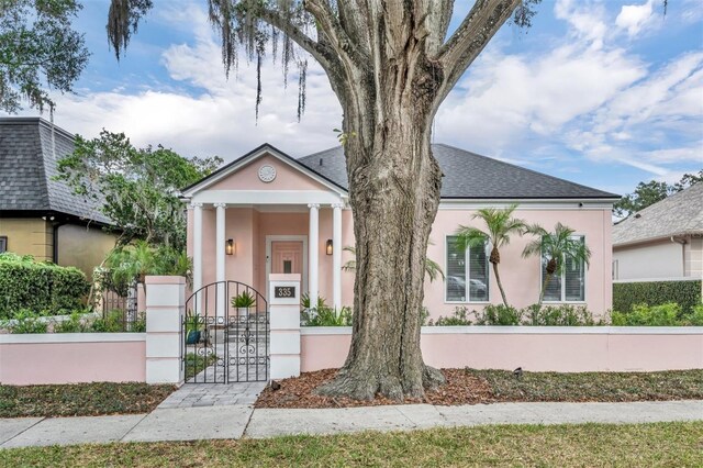 view of front of home with stucco siding, roof with shingles, a fenced front yard, and a gate