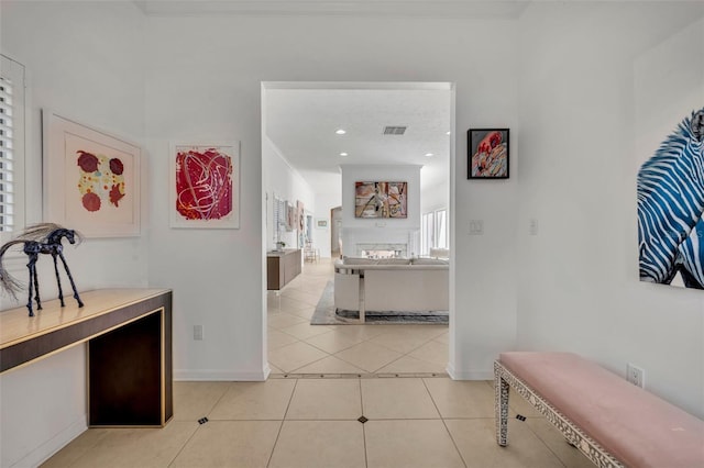 hall with visible vents, baseboards, and light tile patterned flooring