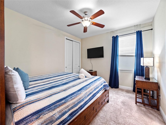 carpeted bedroom with a textured ceiling, a closet, and ceiling fan