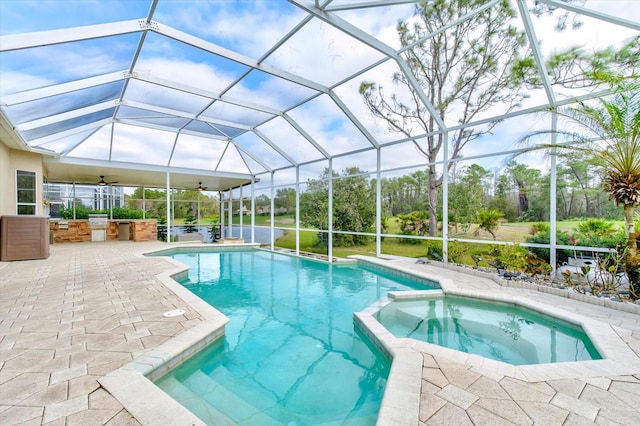 view of pool with exterior kitchen, a pool with connected hot tub, ceiling fan, a lanai, and a patio area