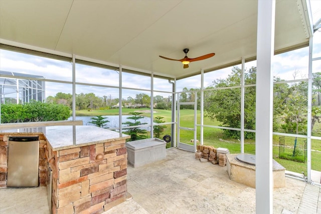 sunroom featuring a water view, ceiling fan, and a healthy amount of sunlight