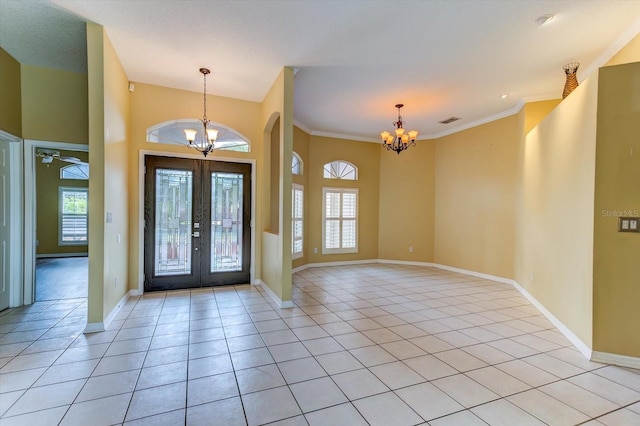 tiled entrance foyer featuring french doors, a healthy amount of sunlight, and a notable chandelier