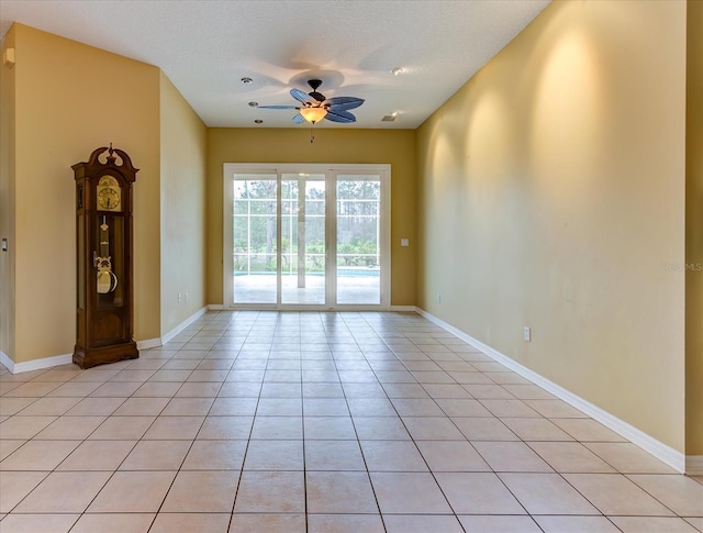 empty room featuring ceiling fan, a textured ceiling, and light tile patterned floors