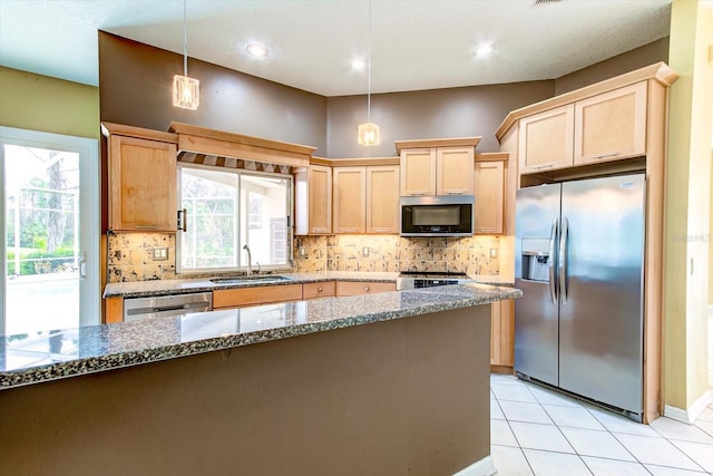 kitchen with sink, hanging light fixtures, stainless steel appliances, tasteful backsplash, and light stone countertops