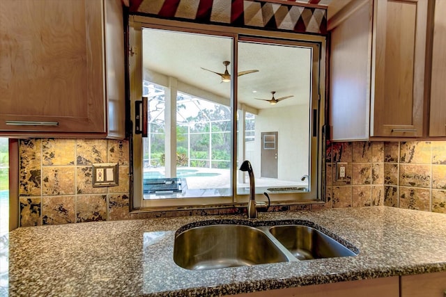 kitchen featuring tasteful backsplash, sink, and dark stone countertops