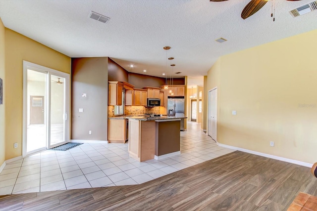 kitchen featuring light tile patterned flooring, appliances with stainless steel finishes, decorative backsplash, hanging light fixtures, and a center island